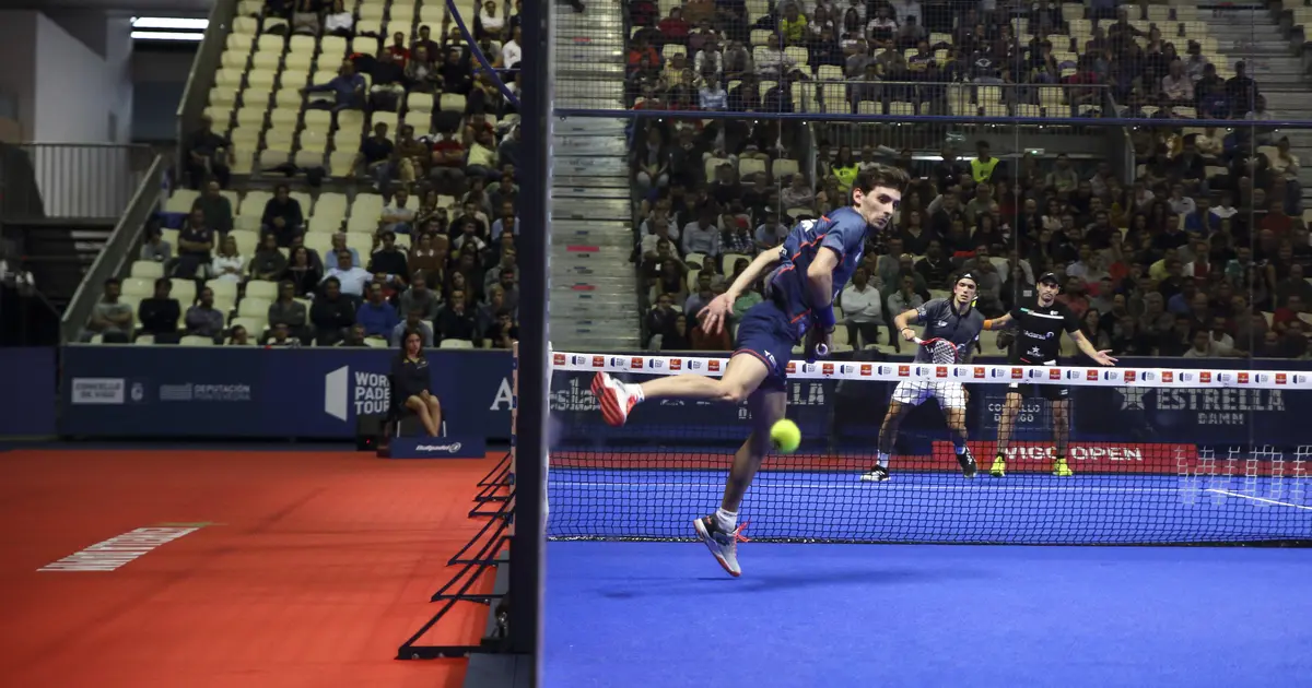 A padel player executing a bajada — taking the ball off the back wall on the way down
