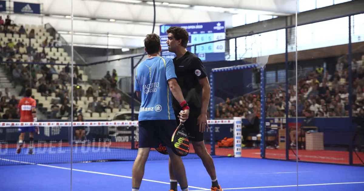 A padel player exiting through the court door to chase a ball that has left the court